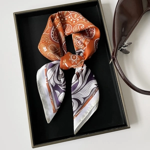 Detail of silk-like paisley square scarf in orange and purple on a luxury tray