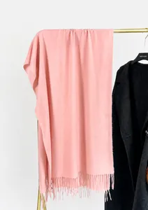 Detail of pink cashmere-feel scarf with soft fringe hanging on a metal hanger