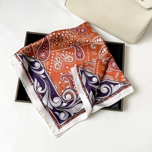 Macro detail of silk-feel orange paisley scarf with purple patterns in a black gift box