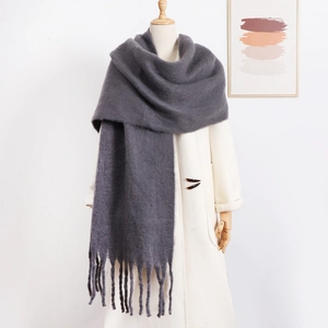 Macro view of thick dark grey mohair scarf with long tassels over a wool coat