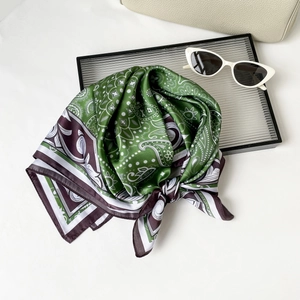 Close-up of green paisley silk scarf with purple border and vintage sunglasses on white table