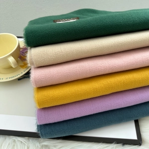 Close-up of stacked soft cashmere-like scarves in multiple colors for winter warmth