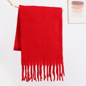 Close-up of soft red mohair scarf texture with long tassels hanging on a wood branch
