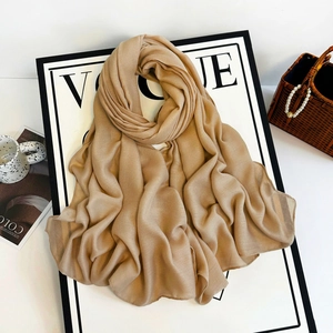 Detail of elegant beige long scarf with fine texture displayed on minimalist fashion props