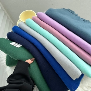 Detailed close-up of multiple colorful cashmere-feel scarves with soft fringe details