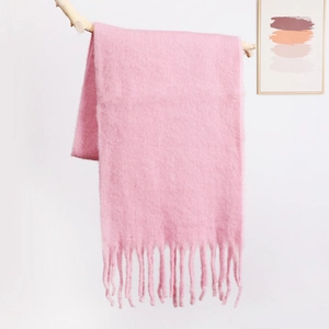 Close-up of soft pink mohair scarf with delicate long tassels on a wooden branch