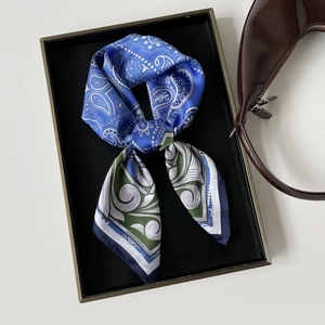 Detailed view of paisley silk scarf with blue and green patterns on a display tray