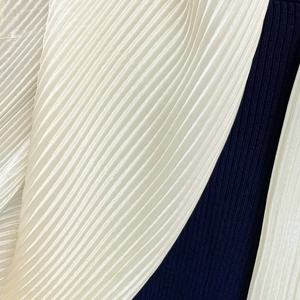 Macro detail of pleated satin silk scarf showing off-white and navy blue fabric textures