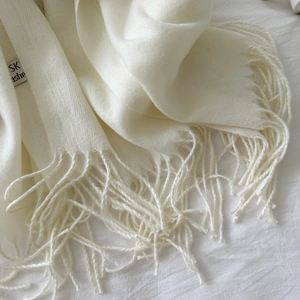 Detailed macro view of ivory cashmere scarf with delicate twill weave and long fringe