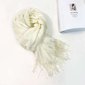 Detail of soft cream-colored scarf featuring premium fabric and elegant long tassels
