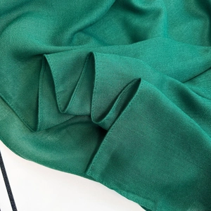 Close-up of emerald green faux cotton linen hijab scarf with fine woven texture detail