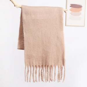 Close-up of soft mohair knit scarf with long fringe details on minimalist wooden branch