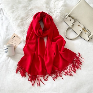 Close-up of vibrant red cashmere-feel scarf with long handmade fringe on white background