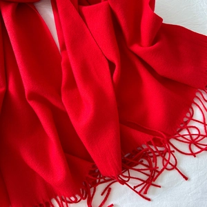 Macro view of vivid red knitted cashmere-like scarf with soft handmade tassels