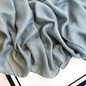 Detailed view of dusty blue linen-like fabric with fine stitching and soft drape texture