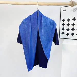 Detail of bright blue pleated silk scarf texture draped over navy ribbed knitwear