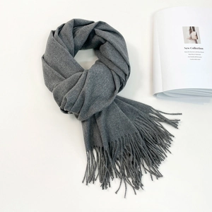 Detail of dark grey cashmere-like scarf showing soft knit texture and fringe tassels