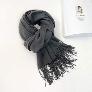 Close-up of a dark grey cashmere-style scarf with fine twill texture and long tassels