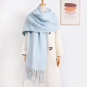Detail view of a thick light blue mohair scarf with tassels on a white coat mannequin