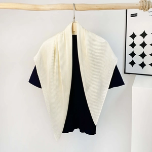 Close-up of pleated beige silk scarf texture hanging on a wooden rod with minimalist decor