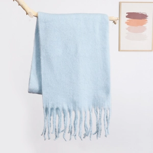 Detail shot of light blue mohair scarf featuring long fringe tassels and soft plush texture