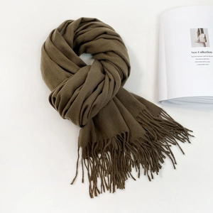 Detail of soft cashmere-like scarf fabric with long tassels in a dark olive color