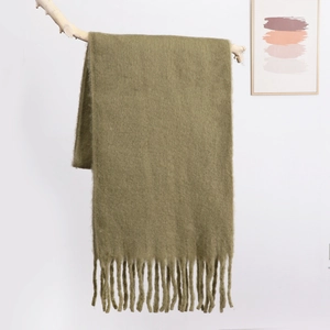 Close-up of olive green mohair scarf with thick fringe draped on a branch