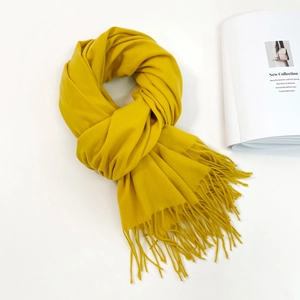 Detail of vibrant yellow scarf featuring soft fringe ends and thick cashmere-like texture