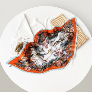Detailed close-up of pleated silk scarf with floral pattern and orange border detail