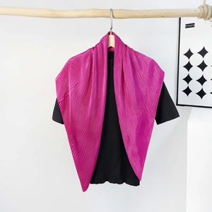 Detail of magenta pleated silk scarf styled over a black top for a fashion-forward look