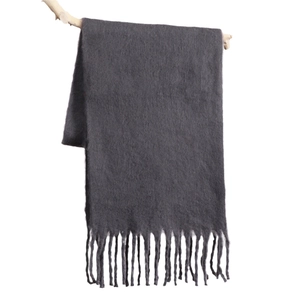 Dark gray mohair scarf with tassels hanging on a branch, soft winter neckwear