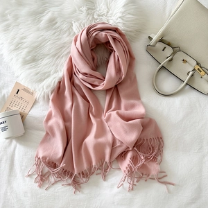 Detail of pink cashmere-like scarf with fringe texture on a cozy white background