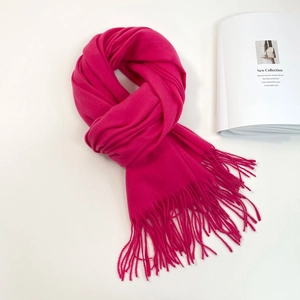 Detail shot of rose red scarf with long fringe tassels on white decorative background