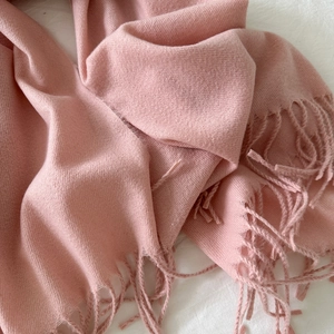 Close-up of soft pink cashmere scarf with high-quality handmade tassels and fine texture