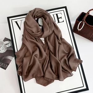 Detailed texture of dark brown chiffon scarf draped over a fashion magazine board