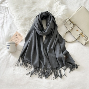 Detailed view of dark grey faux cashmere scarf featuring long tassels and soft texture
