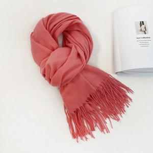Close-up of soft coral pink pashmina scarf with elegant fringe detail and fashion magazine