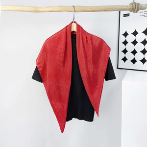 Close-up of pleated texture on deep red satin scarf paired with a black knit top