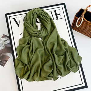 Detail view of army green linen scarf folded on a fashion magazine background