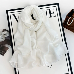 Detailed close-up of a white linen chiffon scarf with elegant pearl decor and vogue styling