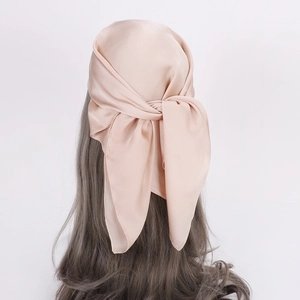 Rear view of a champagne satin silk scarf tied on long wavy hair over a white background