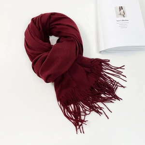 Detail of burgundy pashmina scarf with long fringes and soft knit texture on white background
