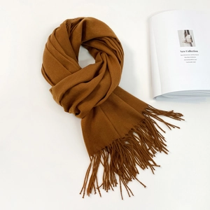 Detailed view of the soft caramel cashmere-feel scarf with fringe ends on a white background
