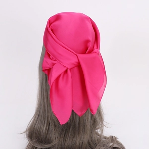 Detail of rose red satin scarf tied as a headband on long curly hair with silky finish