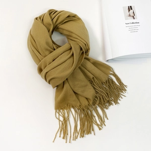Detailed flat lay of a thick ginger yellow knit scarf with long fringes and fashion magazine
