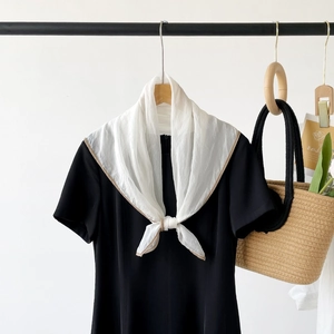 Detail of white semi-transparent scarf with coffee edges paired with a black dress