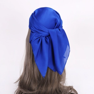 Detail of royal blue satin headscarf tied into an elegant bow with a glossy silk texture