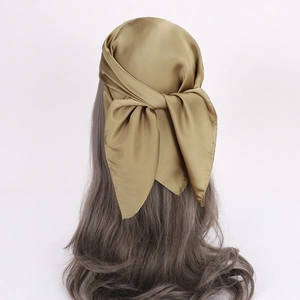 Detail showing the bronze gold satin texture and elegant knotting style of the headscarf