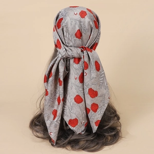 Detail of grey silk scarf featuring red poppy flower patterns tied on a mannequin head