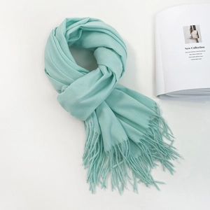 Detail of soft mint green cashmere-like scarf showing delicate fringed edges and texture